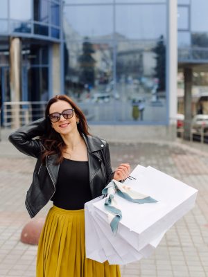 Portrait of young pretty stylish girl holding the shopping bags and looking forward in a good mood. Ideal shopping.